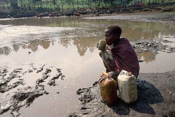 Child holding one glass of dirty water and one of clean water illustrating water quality contrast